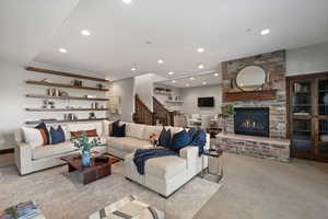 Living room featuring light colored carpet, a stone fireplace, and recessed lighting