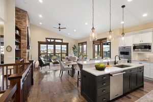 Kitchen featuring two tone color scheme, a breakfast bar, hanging light fixtures, lofted ceiling, and stainless steel appliances