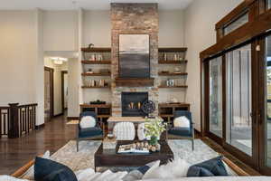 Living room with wood finished floors, a high ceiling, and a fireplace
