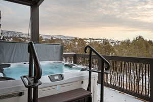 Snow covered deck featuring a hot tub and a mountain view