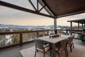 Snow covered deck featuring a mountain view, outdoor dining space, and grilling area