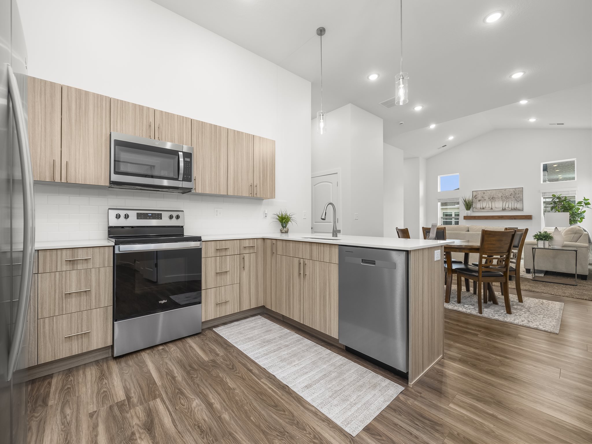 Kitchen with Midtone cabinets, tile backsplash, pendant lighting and quartz counters. *Fridge not included