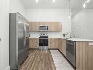 Kitchen with Midtone cabinets, tile backsplash, pendant lighting and quartz counters. *Fridge not included