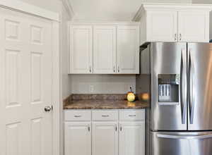 Kitchen with stainless steel fridge with ice dispenser and white cabinetry