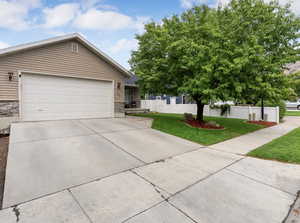 Ranch-style house featuring stone siding, driveway, and a garage