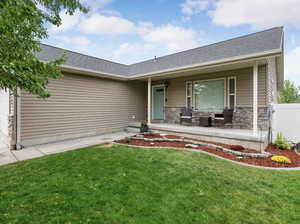 View of front of house with covered porch, roof with shingles, a garage, and stone siding