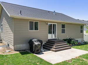 Back of house featuring a lawn, roof with shingles, and a patio