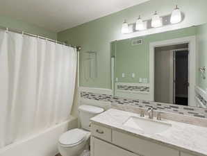 Bathroom featuring vanity, shower / tub combo, backsplash, and a textured ceiling