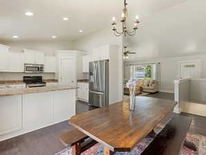 Dining room featuring lofted ceiling, dark wood finished floors, suspended lighting, and a ceiling fan