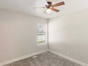 Empty room with carpet flooring, a textured ceiling, and a ceiling fan