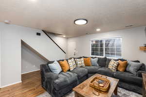 Living area featuring wood finished floors, a textured ceiling, and recessed lighting