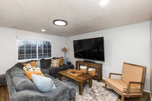 Living room featuring wood finished floors, a textured ceiling, and recessed lighting