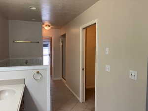 Bathroom featuring a textured ceiling, vanity, light tile patterned flooring, and a stall shower