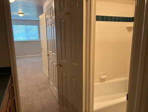 Bathroom with light carpet, a textured ceiling, vanity, and shower / bath combination