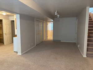 Finished below grade area featuring light colored carpet and a textured ceiling