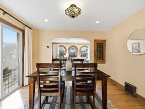 Dining space featuring light wood-type flooring, recessed lighting, and arched walkways