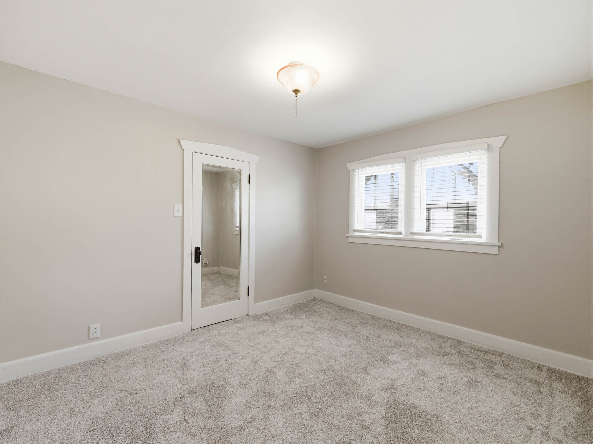 Empty room with light colored carpet and baseboards