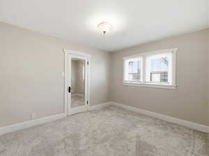 Empty room with light colored carpet and baseboards