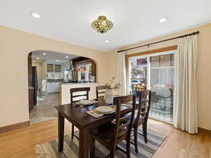 Dining room featuring arched walkways, light wood finished floors, and recessed lighting