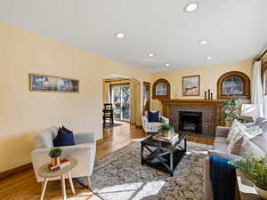 Living area featuring arched walkways, wood finished floors, recessed lighting, and a fireplace