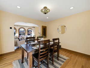 Dining area with arched walkways, recessed lighting, and light wood-style floors