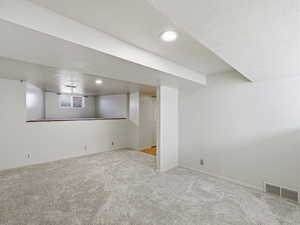 Basement with carpet, a textured ceiling, and recessed lighting