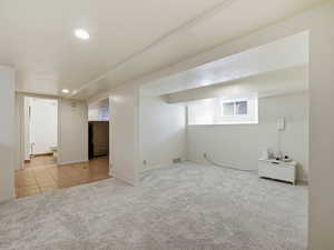 Finished basement with light carpet and recessed lighting