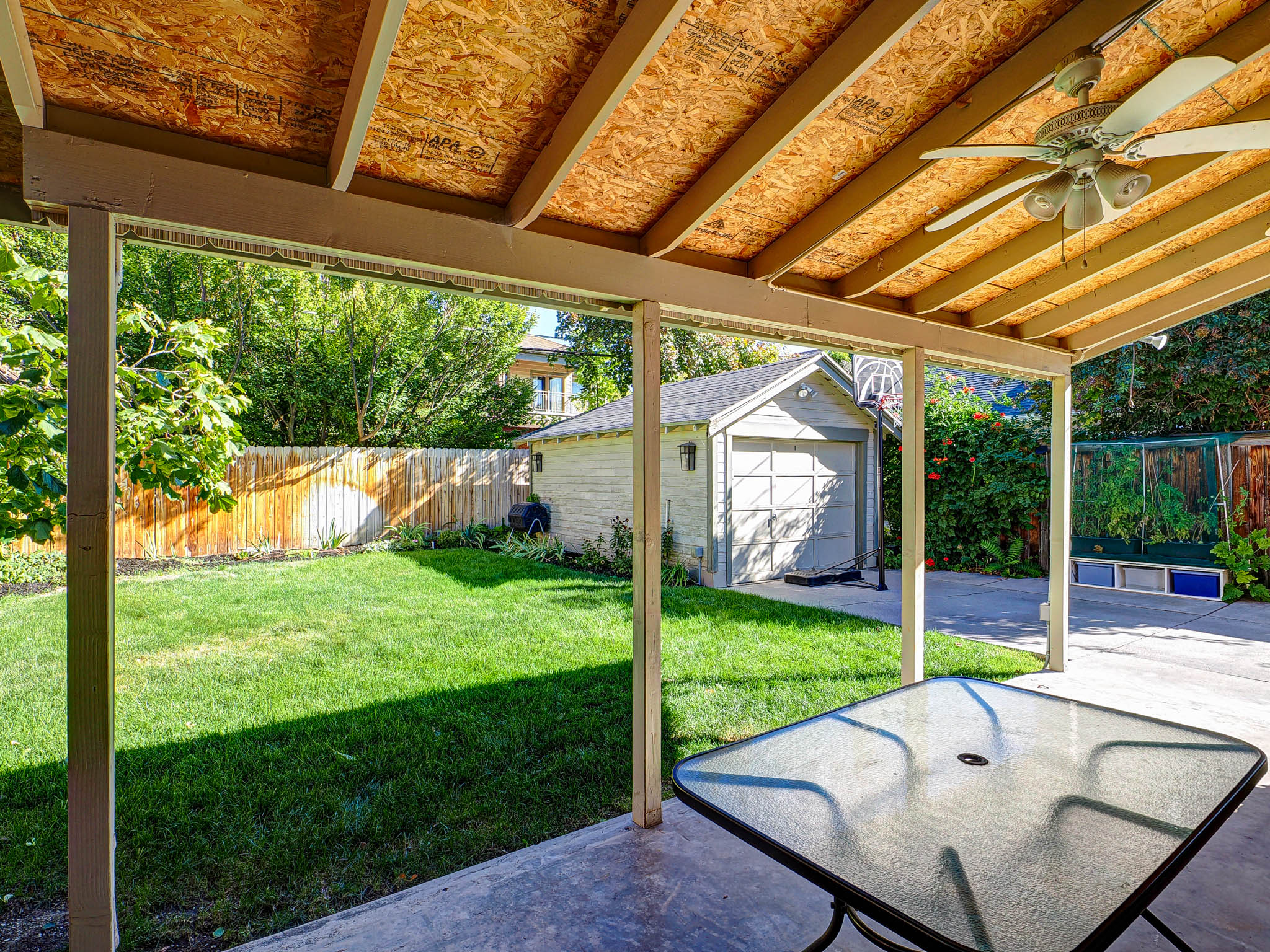 Fenced backyard with an outbuilding, ceiling fan, and a garage