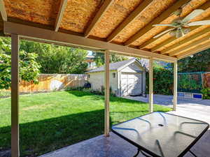 Fenced backyard with an outbuilding, ceiling fan, and a garage