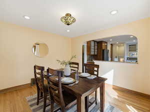Dining space featuring arched walkways, light wood-style flooring, and recessed lighting