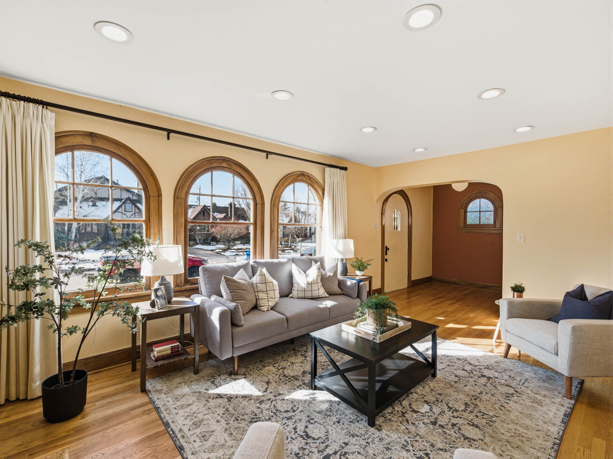 Living area featuring arched walkways, light wood-style flooring, and recessed lighting