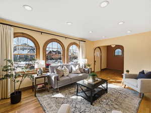 Living area featuring arched walkways, light wood-style flooring, and recessed lighting