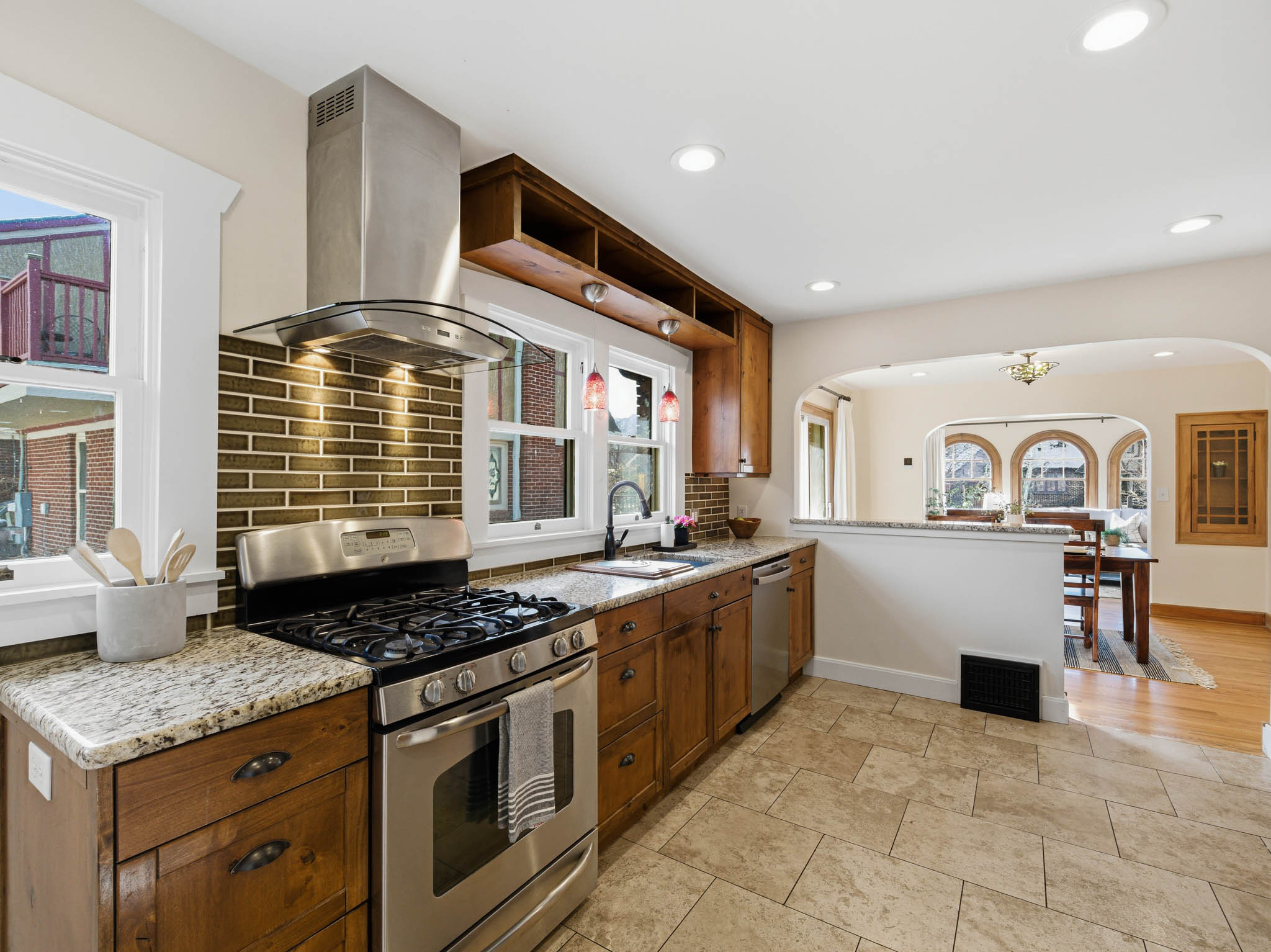 Kitchen with stainless steel appliances, light stone countertops, island range hood, wood finish cabinetry, and recessed lighting