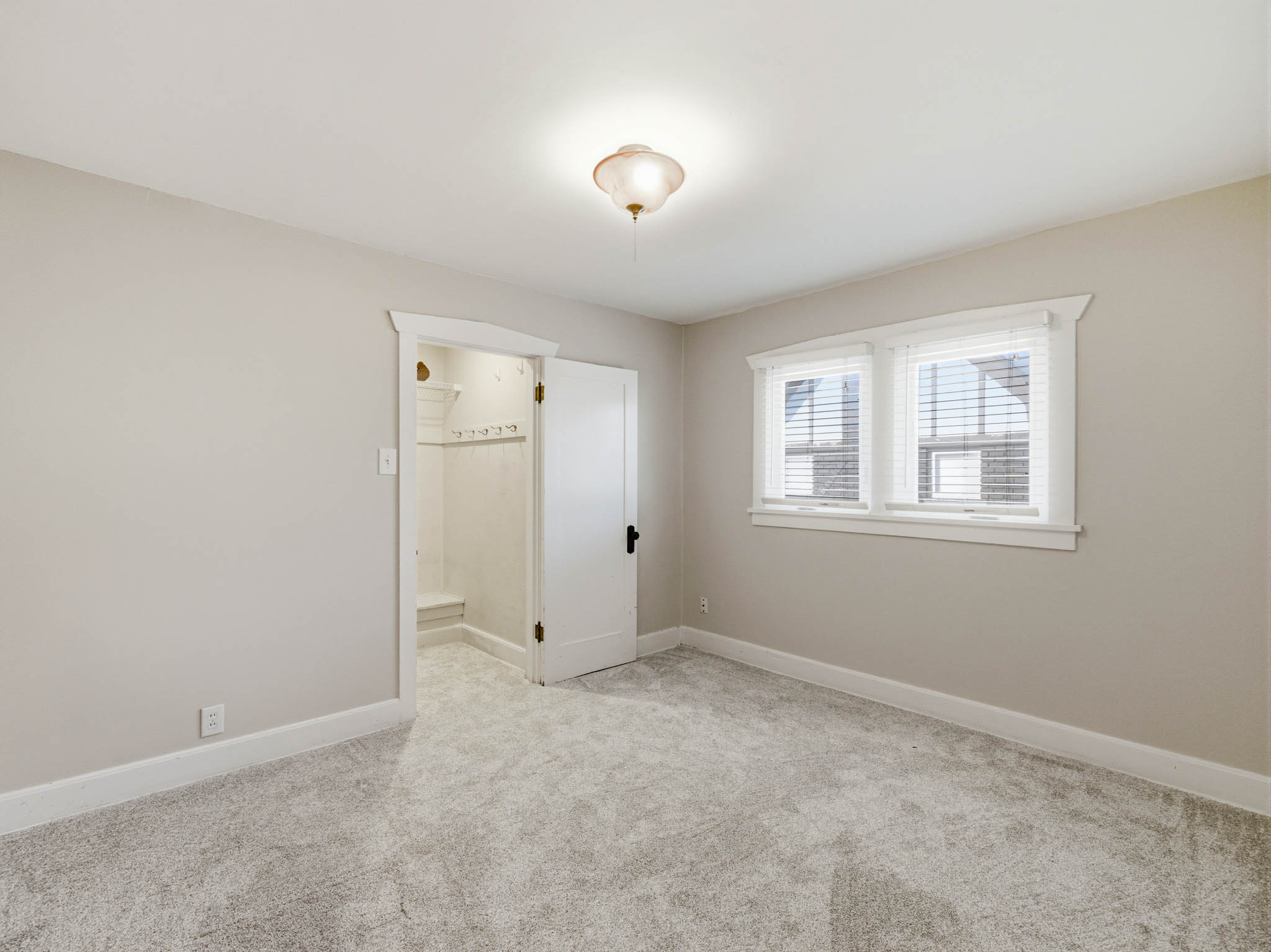 Unfurnished bedroom with light carpet and baseboards