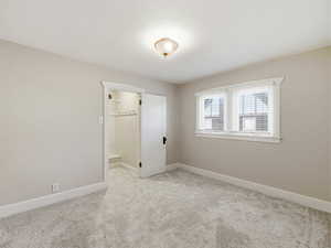 Unfurnished bedroom with light carpet and baseboards