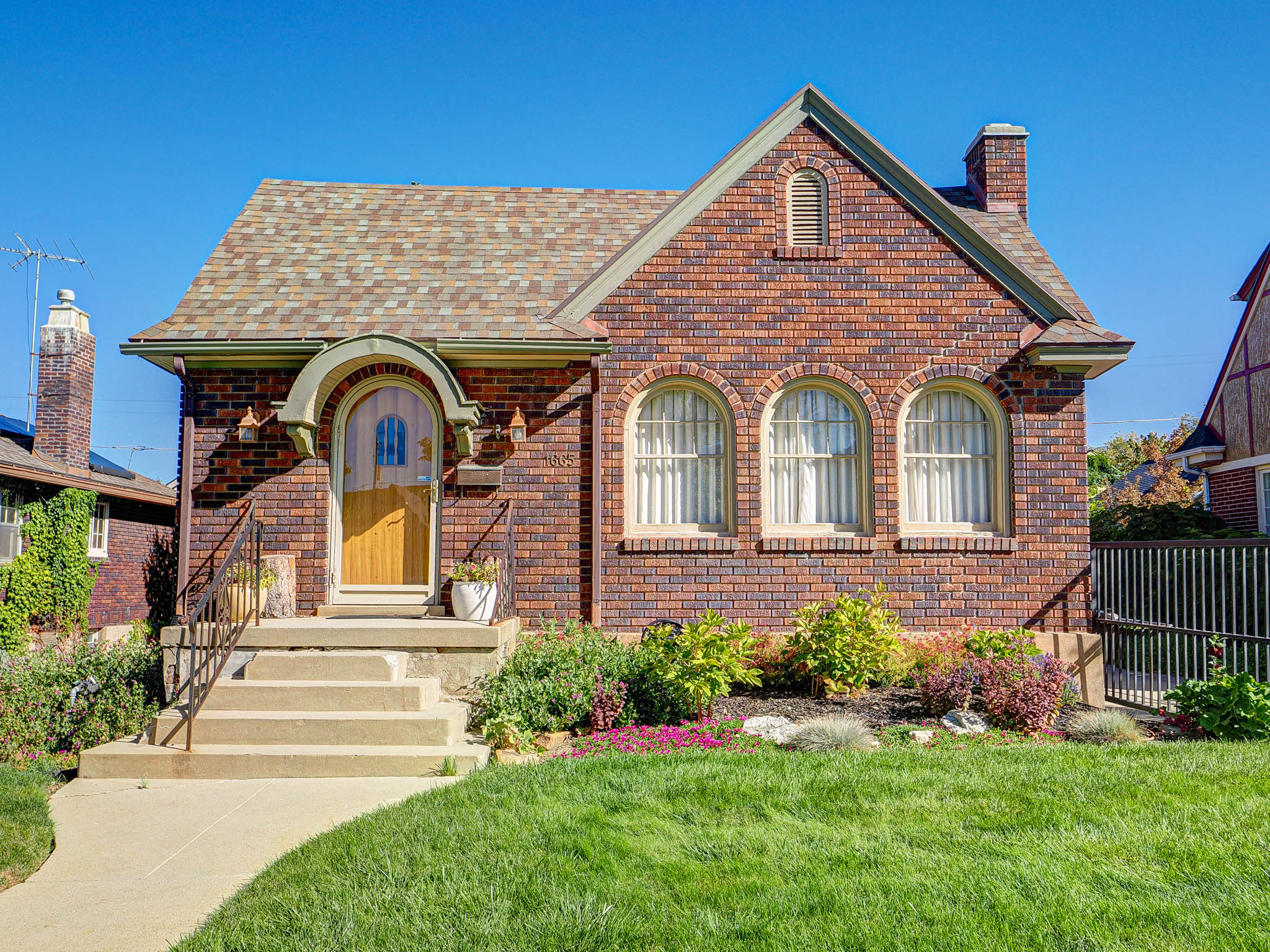 View of front of house featuring brick siding, a shingled roof, and a chimney