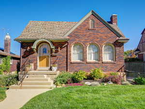 View of front of house featuring brick siding, a shingled roof, and a chimney