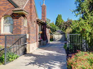 View of side of home with a detached garage, an outdoor structure, a chimney, brick siding, and driveway