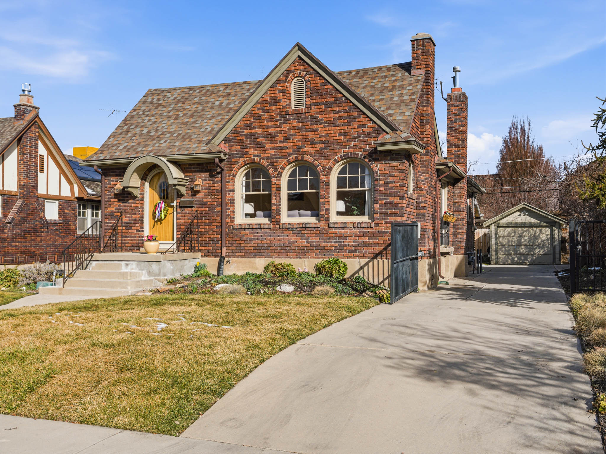 Tudor house with an outbuilding, a front yard, a garage, brick siding, and a chimney