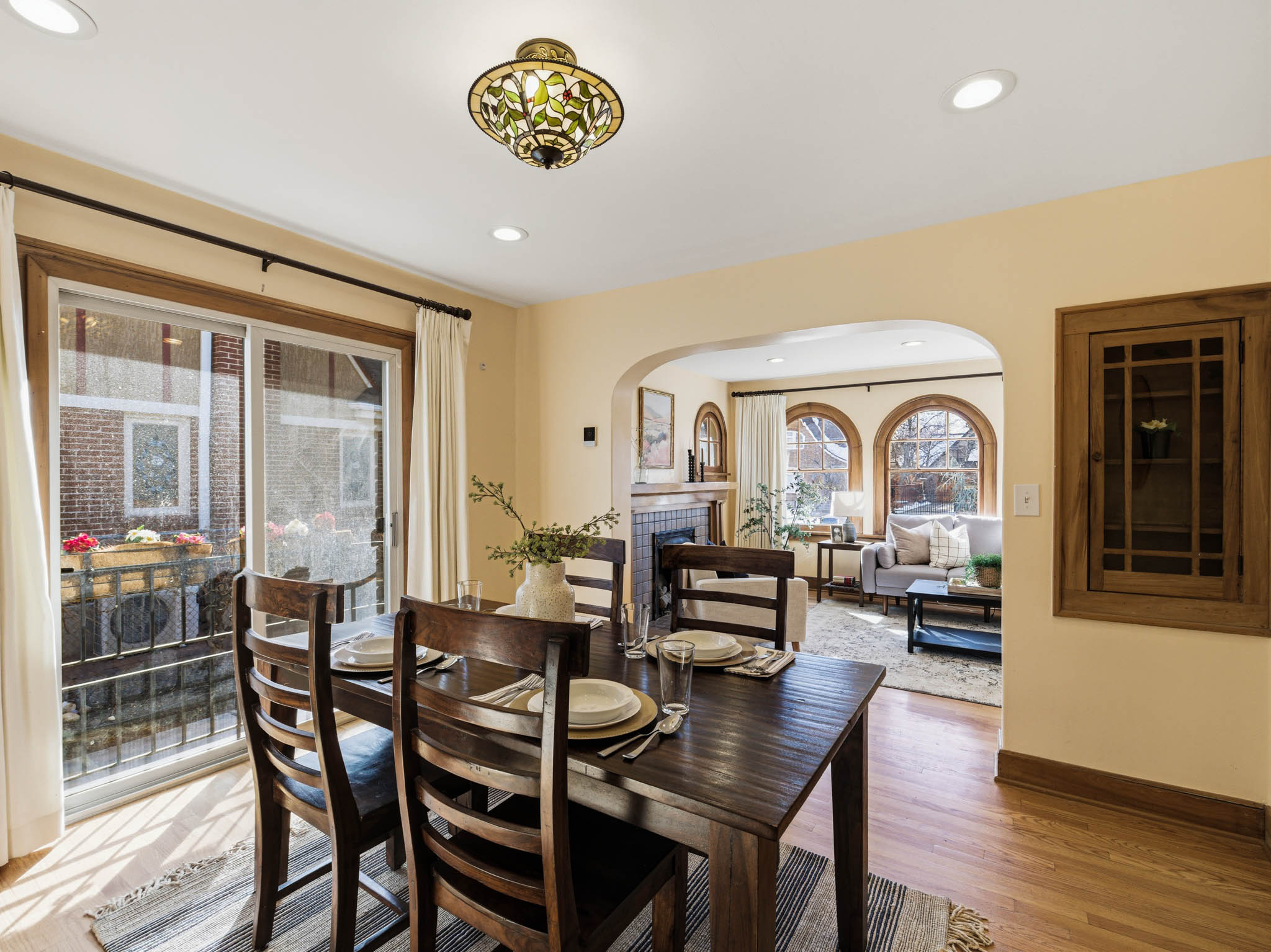 Dining space featuring a tile fireplace, light wood-style floors, arched walkways, and recessed lighting