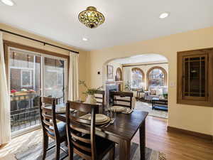 Dining space featuring a tile fireplace, light wood-style floors, arched walkways, and recessed lighting