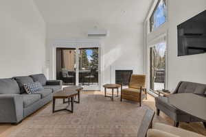 Living room with vaulted ceiling, plenty of natural light, a glass covered fireplace, and light wood finished floors