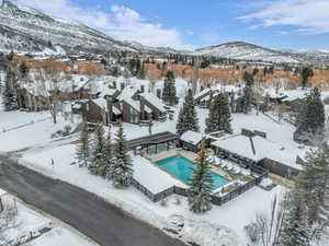 Snowy aerial view featuring a mountain view and view of pool