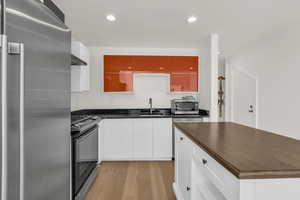 Kitchen featuring stainless steel appliances, light wood-style floors, recessed lighting, white cabinetry, and butcher block counters