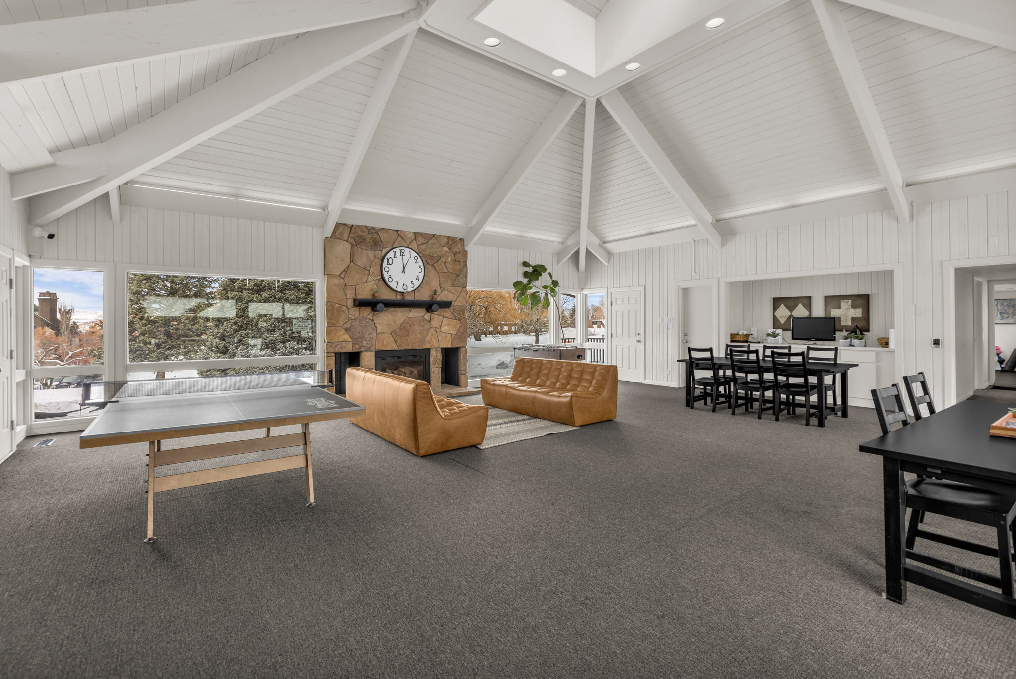 Carpeted living area featuring a stone fireplace, lofted ceiling, and wood walls