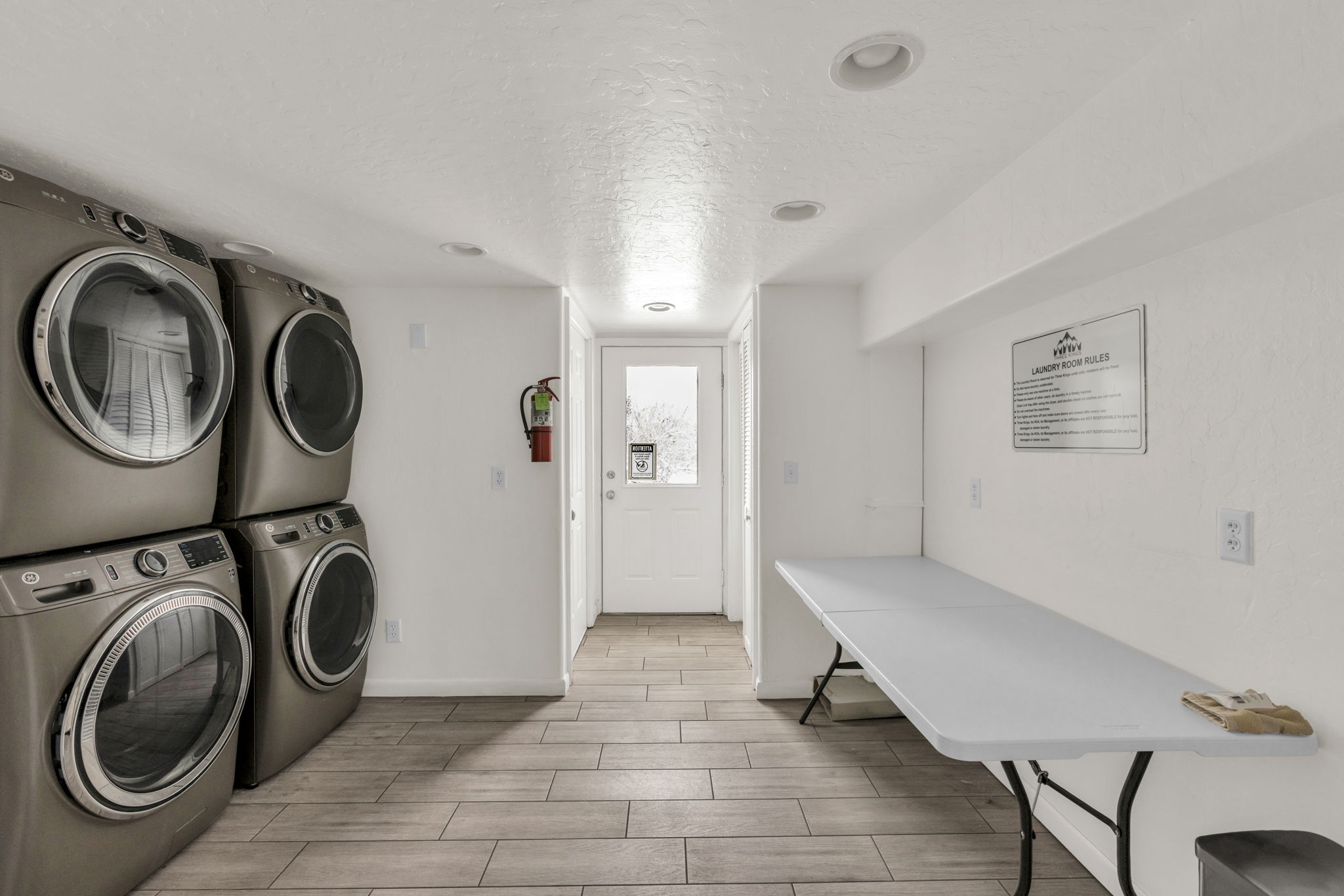Laundry area featuring a textured ceiling, wood tiled floors, and stacked washer and clothes dryer