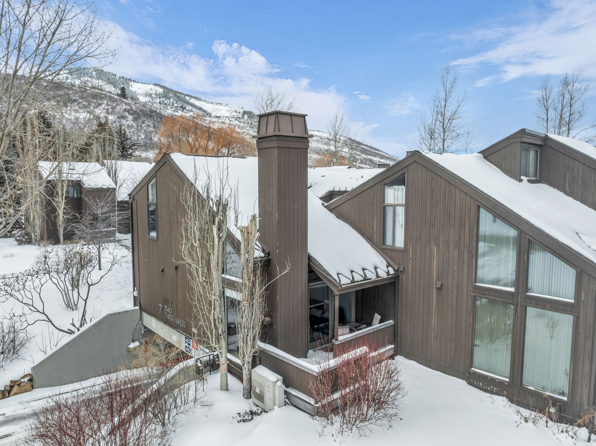View of snowy exterior featuring a deck with mountain view and a chimney