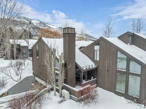 View of snowy exterior featuring a deck with mountain view and a chimney