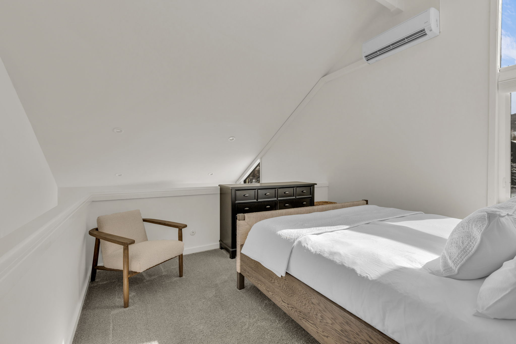 Bedroom with vaulted ceiling, carpet floors, and a wall mounted mini split