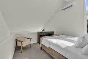Bedroom with vaulted ceiling, carpet floors, and a wall mounted mini split